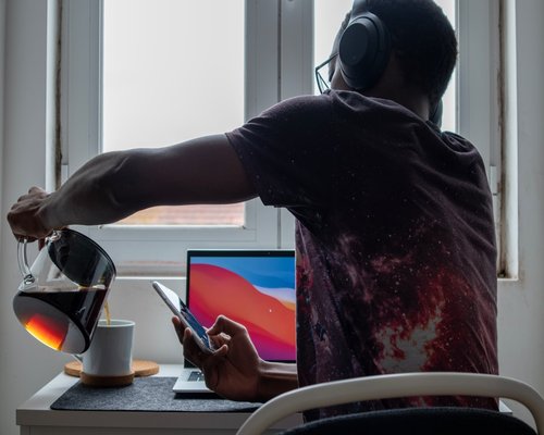 Person typing on laptop near window in home office with a cup of coffee